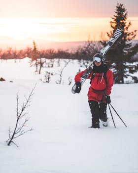 A skier walks through a snowy landscape in Sweden during a vibrant winter sunset.