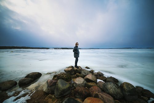 Woman in Puffer Jacket Posing on Rocks in Seaside