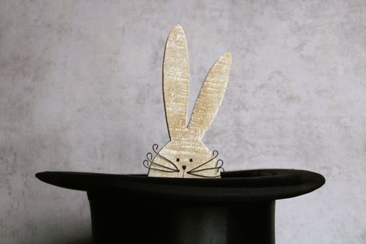 Playful rabbit ears popping from a magician's hat against a gray background creating a whimsical scene.