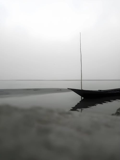 Boat on calm river under grey sky