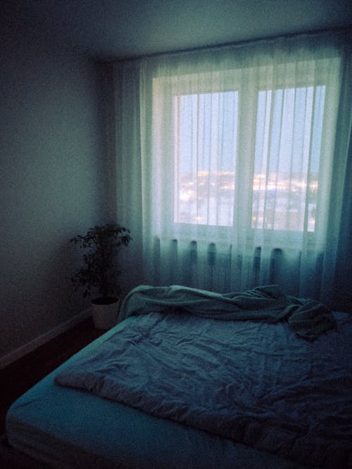A bed with a blue blanket and a window