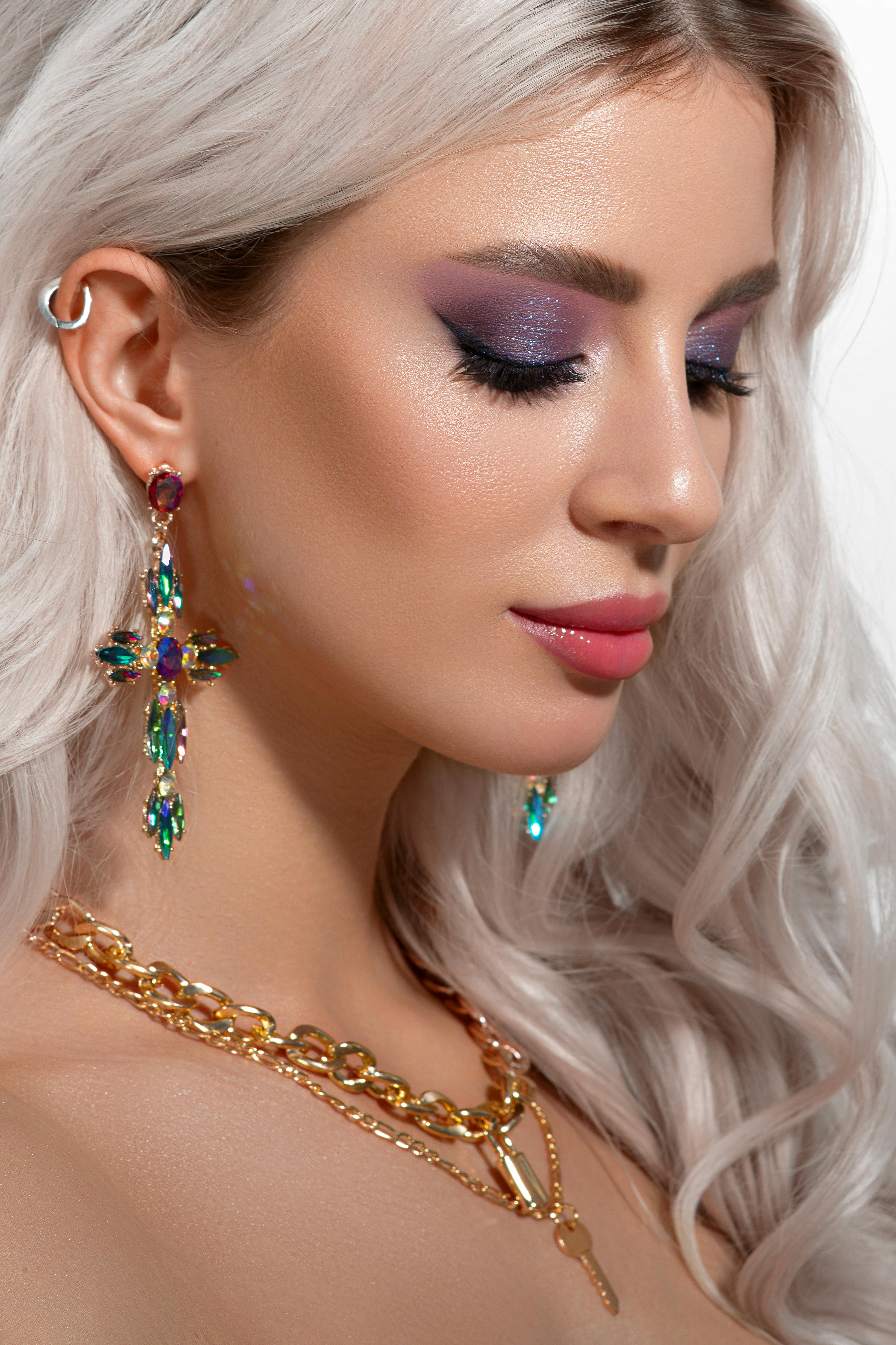 Stunning portrait of a blonde woman with colorful earrings and necklace.