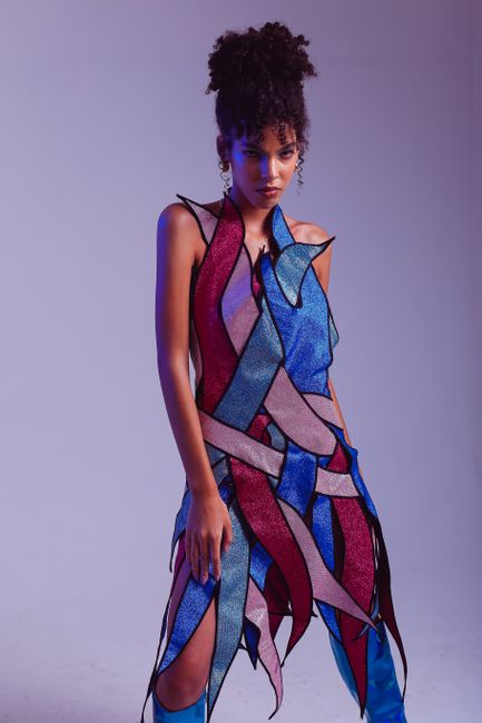 Fashion portrait of a woman in a vibrant, abstract dress and blue boots.