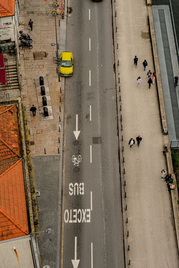 Cena urbana aérea em Porto, Portugal, apresentando um carro amarelo solitário.