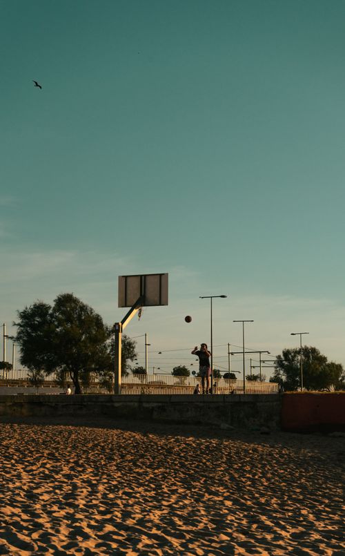 Free A man enjoying a game of basketball on an outdoor beach court in Porto, Portugal under clear skies. Stock Photo