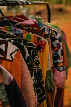Vibrant vintage shirts displayed on hangers, showcasing unique patterns in an outdoor setting.
