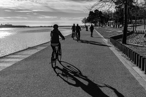 Free Black and white image of people cycling and walking along a riverside promenade in Porto, Portugal. Stock Photo