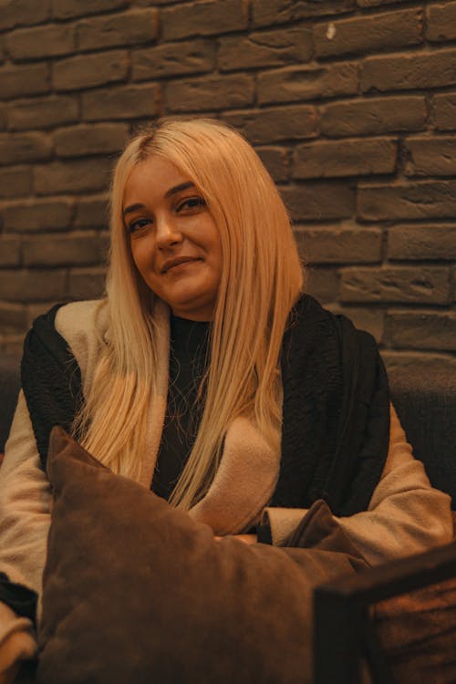 Blonde Woman Holds Pillow on Sofa