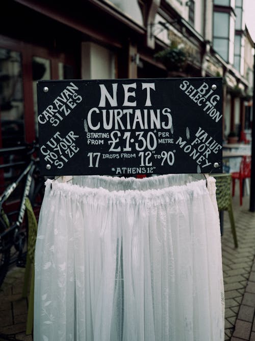 A sign that says net curtains on the sidewalk