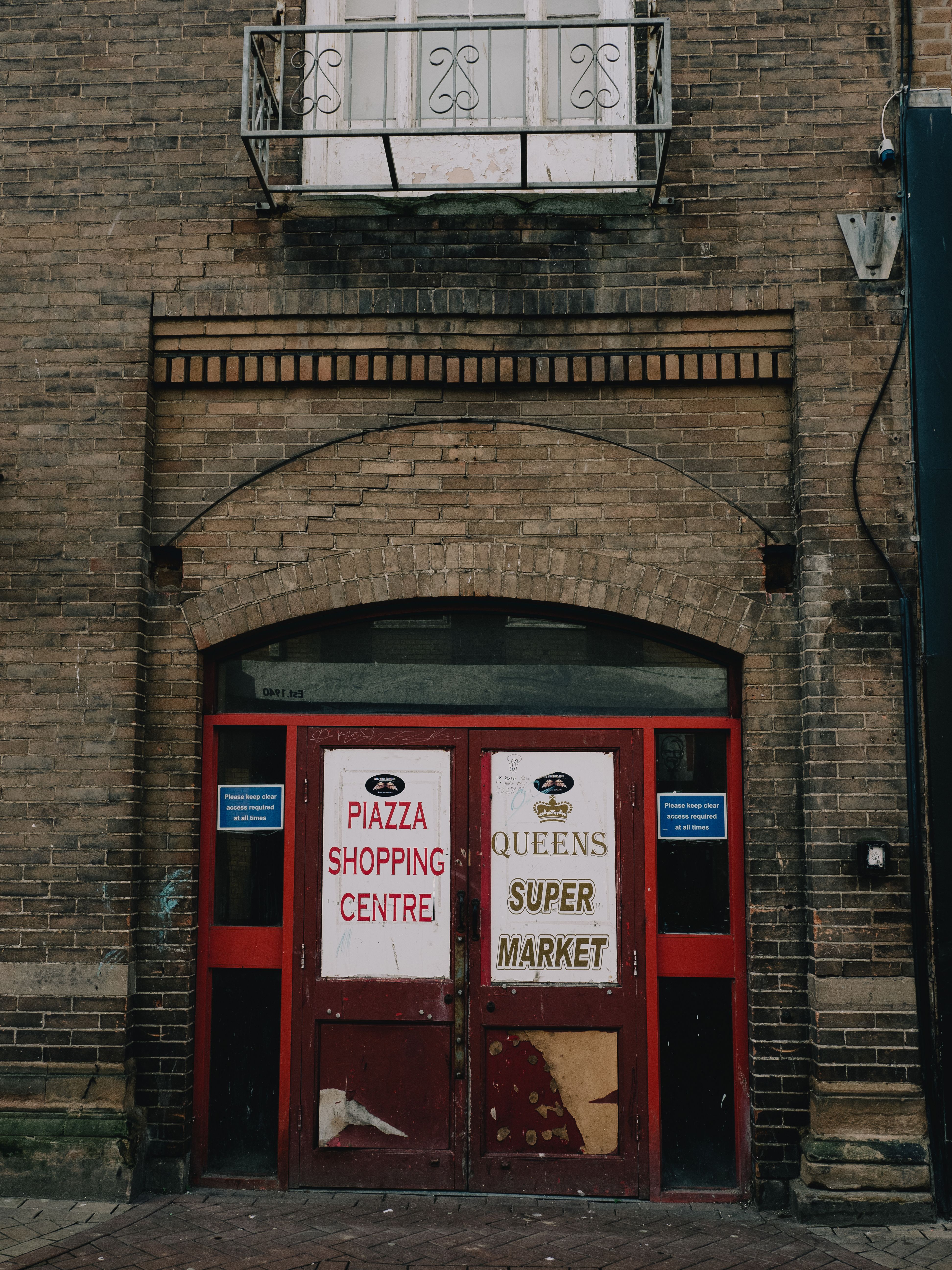 An old red door leading to the Piazza Shopping Centre in an urban setting.