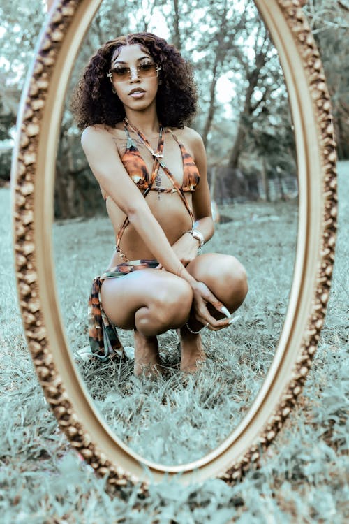 Woman in Bra Squatting by Mirror