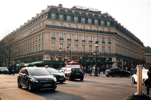 Free A bustling Parisian street scene with cars and pedestrians in front of a historic hotel facade. Stock Photo
