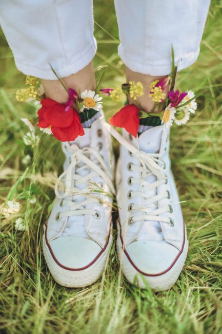 Close-up of white sneakers with wildflowers tucked in, symbolizing spring and nature's embrace.