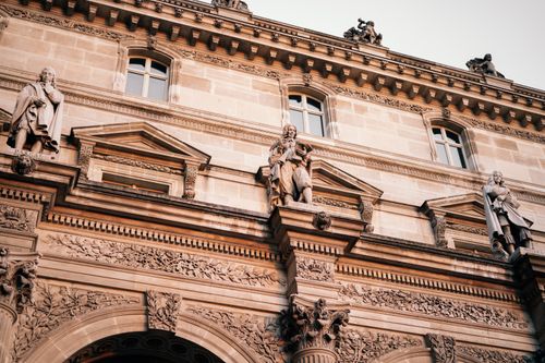 Free Facade of the Louvre Museum in Paris featuring intricate sculptures and classic architecture. Stock Photo