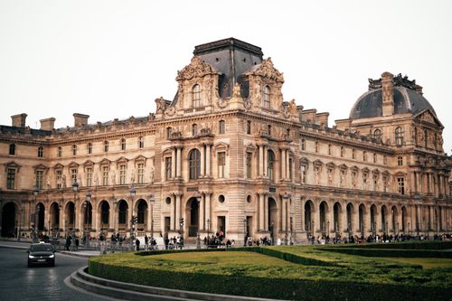 Free Elegant view of the historic Louvre Museum in Paris with warm evening light highlighting the architecture. Stock Photo