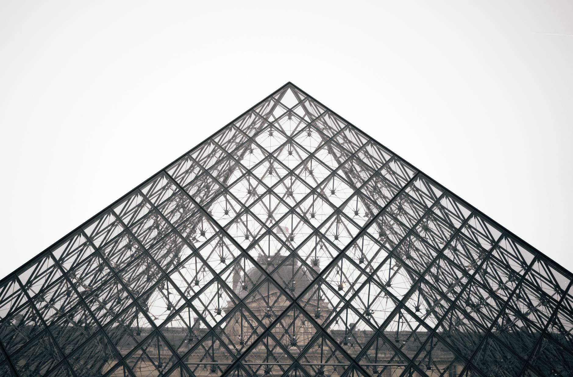 Close-up of the Louvre Pyramid showcasing its modern geometric design against a clear sky in Paris.