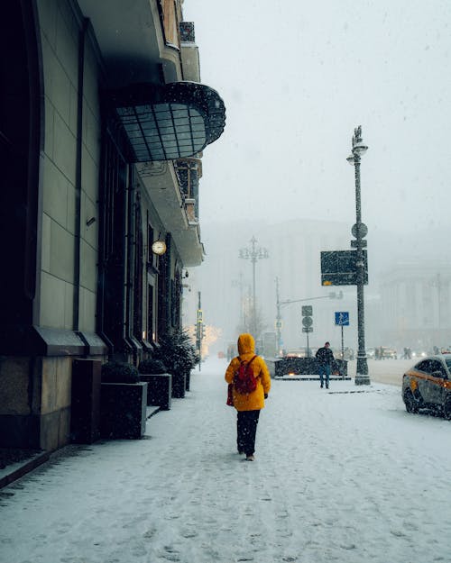 Person with Backpack Walking on Sidewalk in Snow