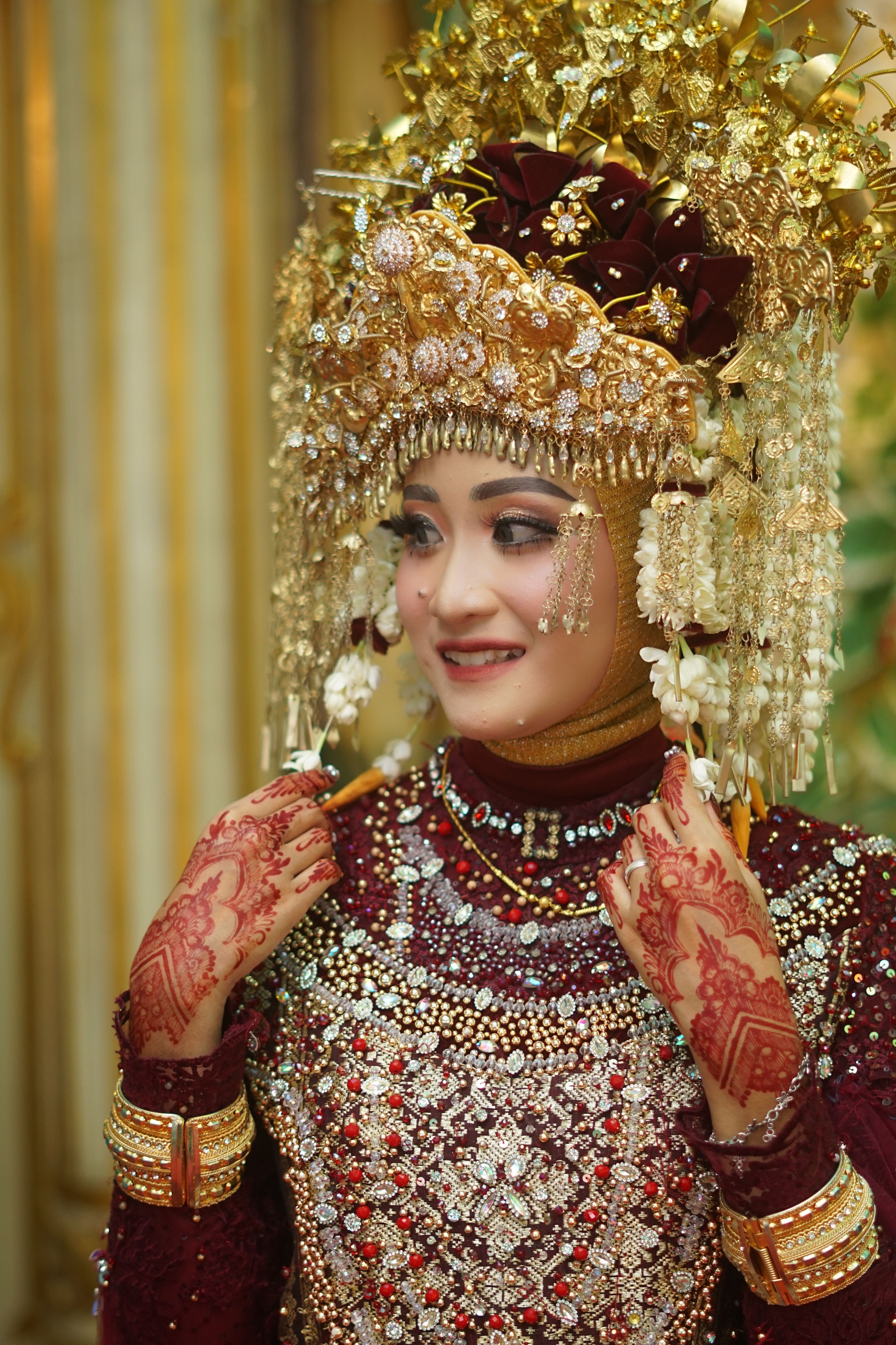 Indonesian bride in traditional attire with intricate headdress and henna tattoos, exuding cultural richness.