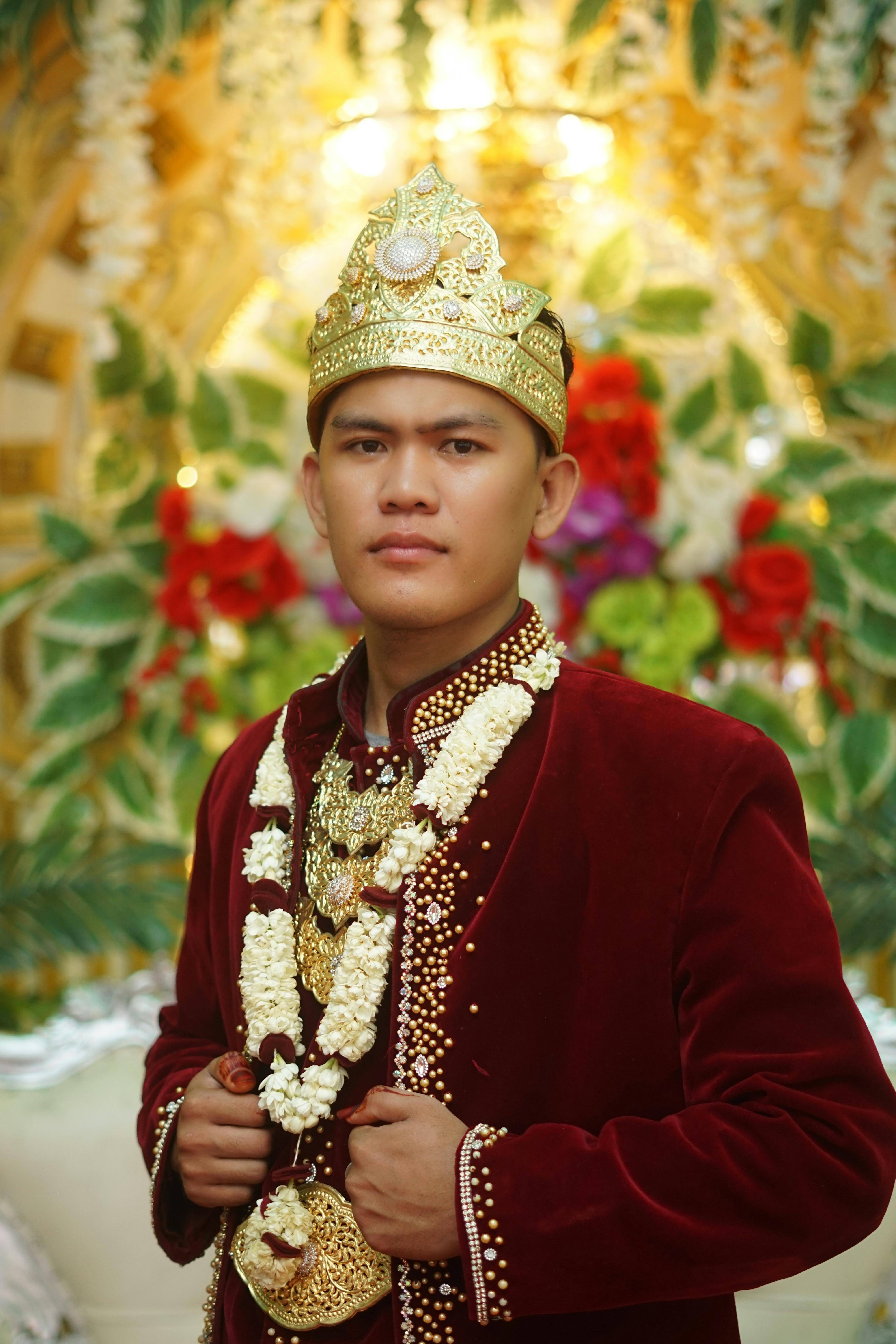 A groom in traditional attire adorned with jewelry and garlands, showcasing cultural elegance.