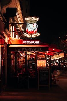 Charming night view of Le Marivaux restaurant in Paris with vibrant neon lights and cozy atmosphere.