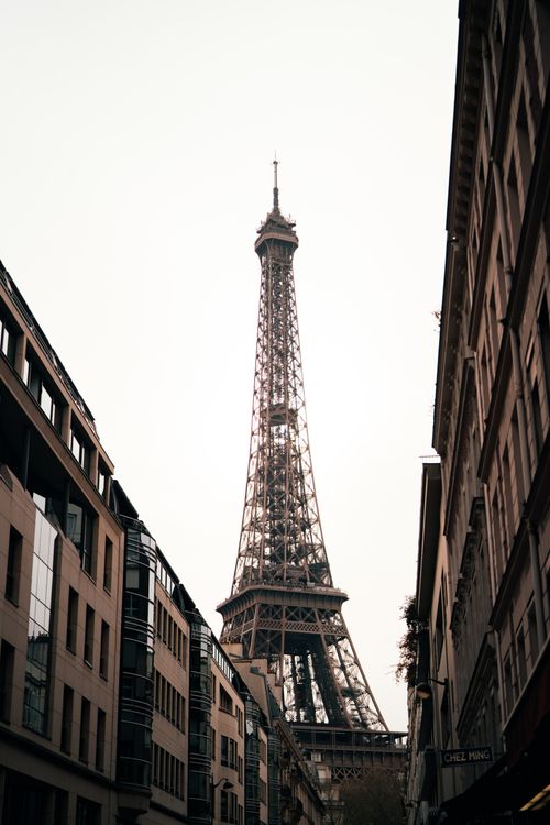 Free Eiffel Tower seen through a Paris street, showcasing iconic architecture. Stock Photo