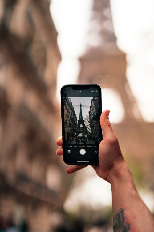 Free A person using a smartphone to photograph the iconic Eiffel Tower in Paris. Stock Photo