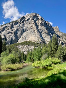 在明亮的蓝天下，高耸的岩石山脉与清澈的河流令人惊叹