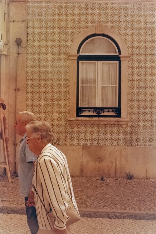 Elderly Couple Walking by Vintage Building Wall