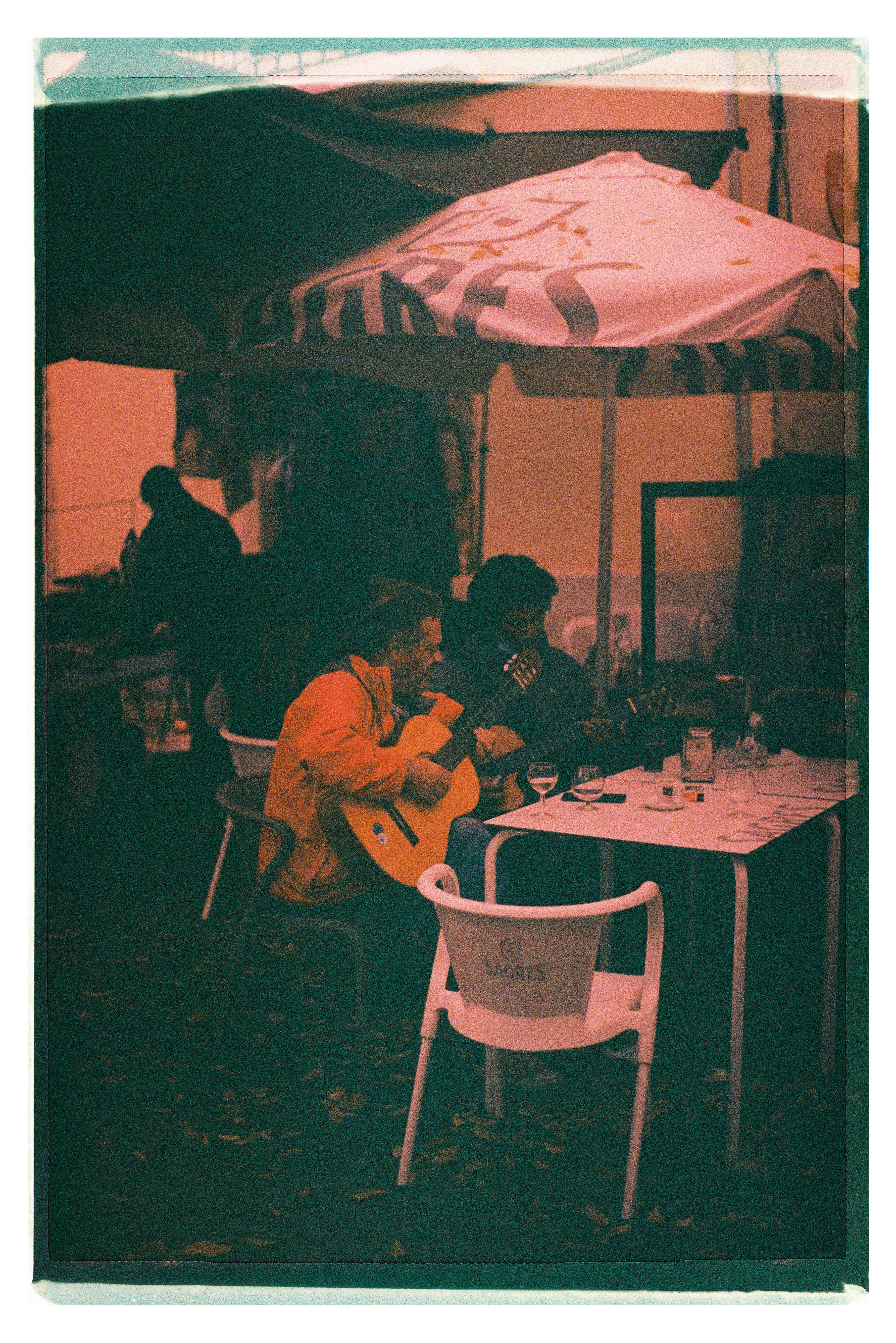 Two guitarists playing at a café in Lisbon, creating a cozy urban atmosphere.