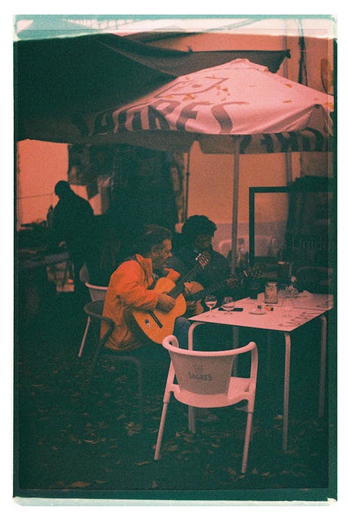 A man sitting at a table under an umbrella