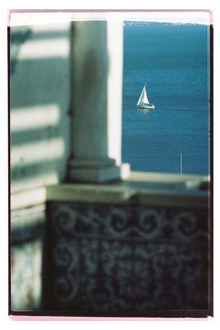 A sailboat on Lisbon's Tejo River framed by intricate architecture, offering a serene travel scene.