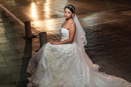 A bride sitting on the ground in the rain