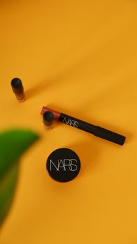Minimalist display of makeup items on a vibrant yellow background, showcasing beauty products.