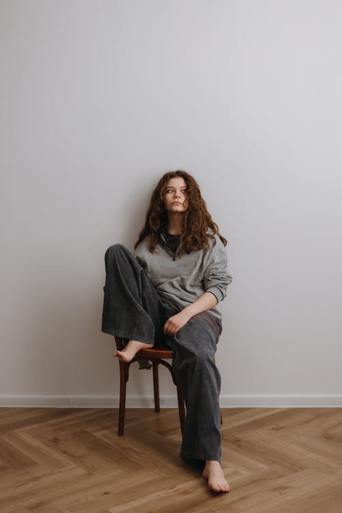 A woman sitting on a chair in a grey sweater