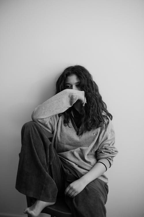 A woman sitting on a chair with her hand on her face