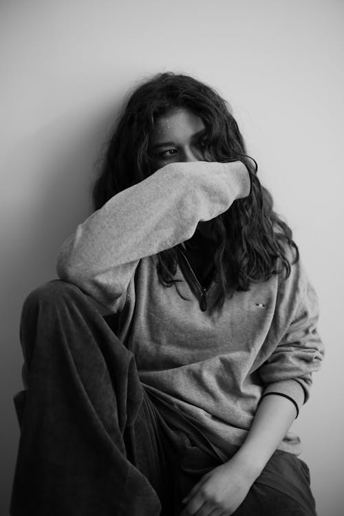 A woman sitting on the floor with her hands on her face