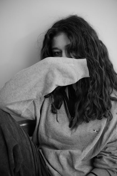 A woman sitting on a chair with her hands on her face