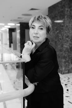 Black and white portrait of a senior woman posing indoors with thoughtful expression.