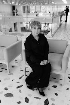 Stylish woman in black sitting indoors showcasing modern elegance in fashion.