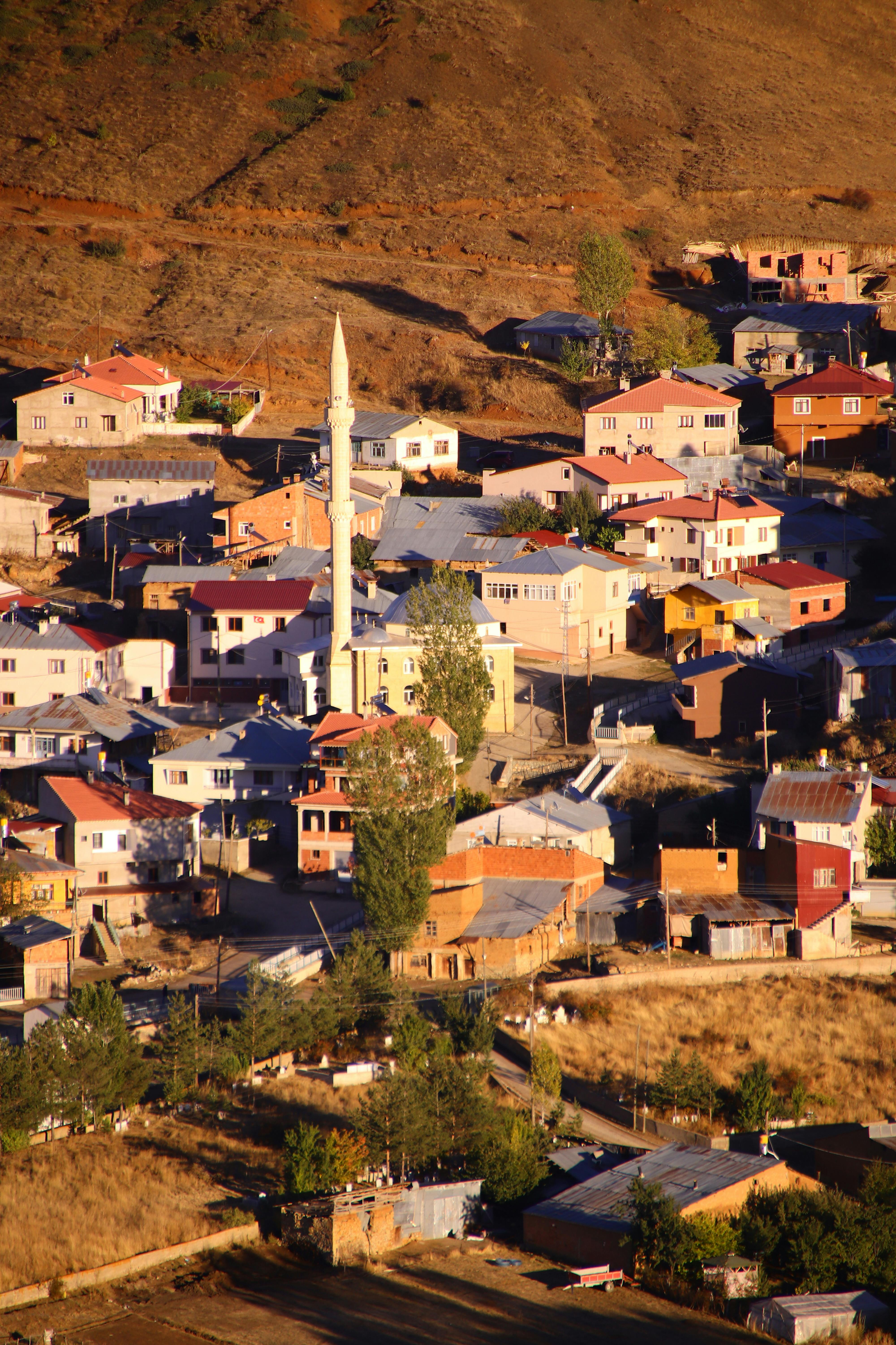Stunning aerial view of a mountain village with a prominent mosque minaret at sunset.