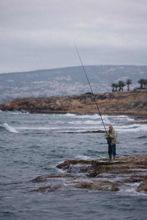 adam, ayakta, Balık tutmak içeren Ücretsiz stok fotoğraf