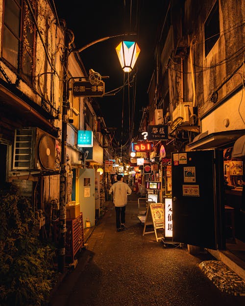A narrow alley at night with lights and people