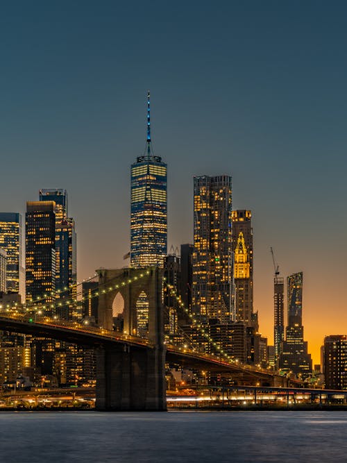 The new york skyline at dusk with the brooklyn bridge in the background