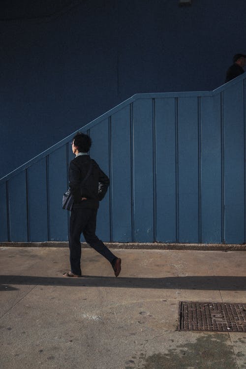 Man Walking near Blue Wall