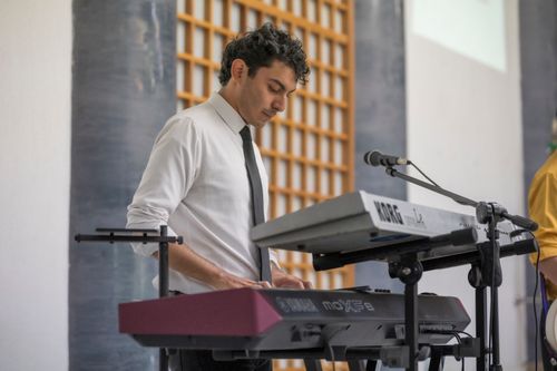 Free A man in a tie playing a keyboard at an indoor event, focusing on musical performance. Stock Photo