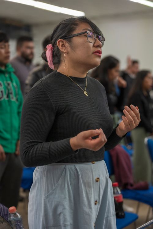 Free Focused woman with eyeglasses praying during a group gathering indoors. Stock Photo