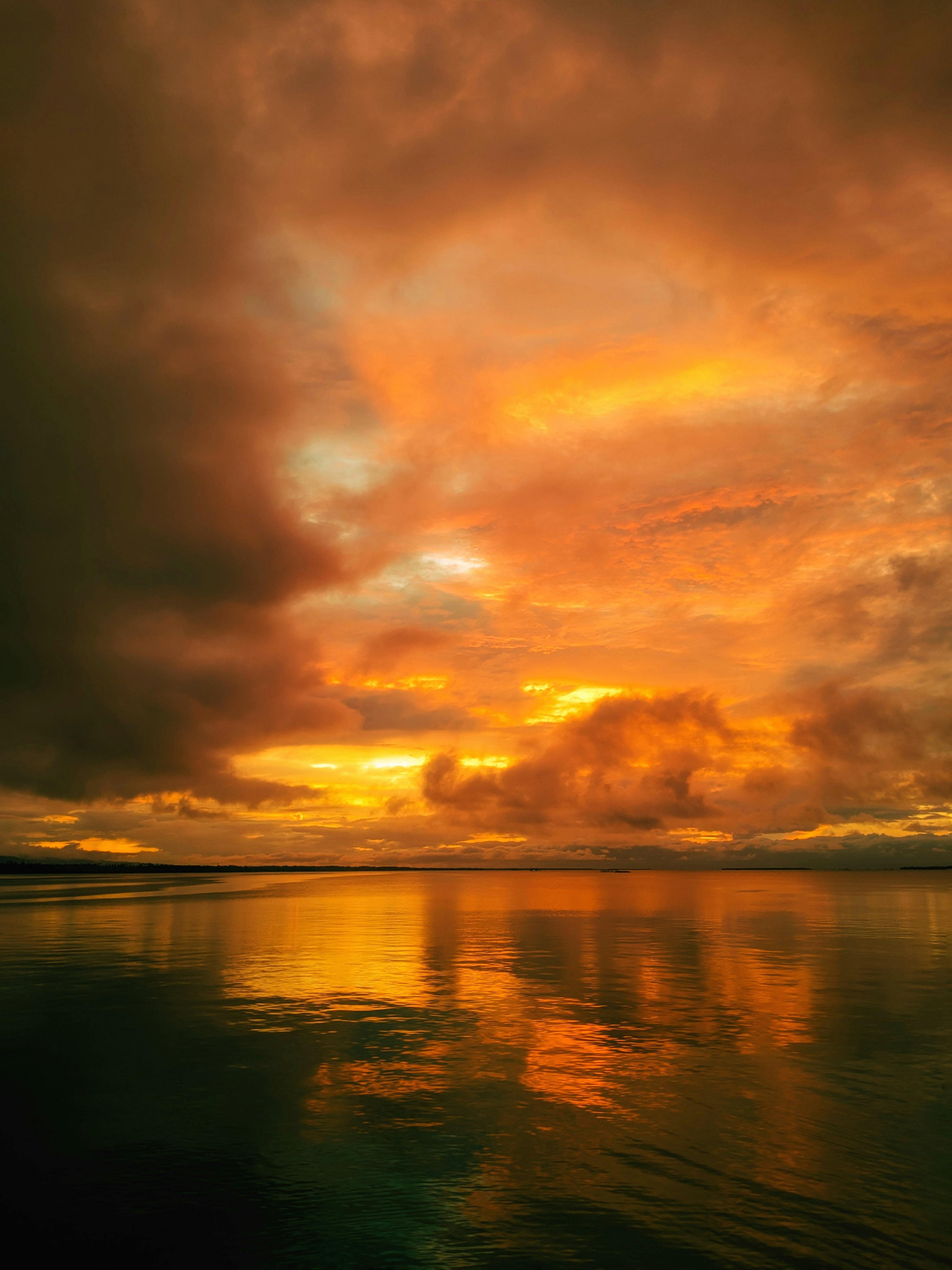 Stunning sunset over the ocean with vibrant orange and yellow hues reflecting on calm waters.