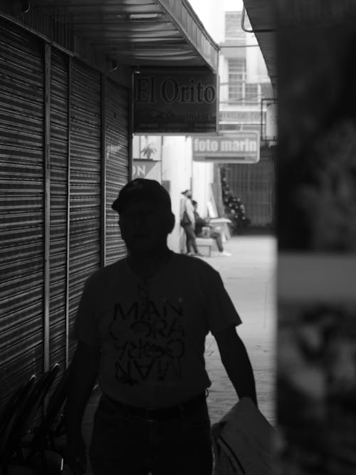 Silhouette of a Man between Closed Market Kiosks