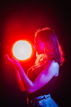 一张女子手持发光球体的侧面图，球体发出鲜艳的红光，非常适合创意项目