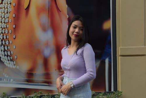 Photo of a Young Woman Wearing a Lilac Blouse, Posing against a Banner